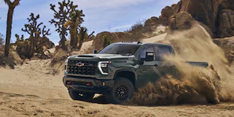 a green 2026 Chevy Silverado HD 2500 kicks up dirt in Orange, CA